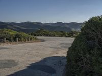 a scenic shot of the road going up hill side to the ocean on a beautiful day