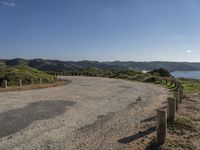 an empty road near some hills with mountains in the background with a blue sky with no clouds