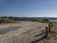 an empty road near some hills with mountains in the background with a blue sky with no clouds