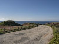 a view of a paved road in the middle of the day with the ocean in the background