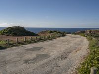 a view of a paved road in the middle of the day with the ocean in the background