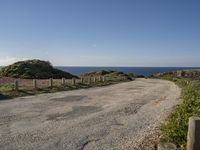 a view of a paved road in the middle of the day with the ocean in the background