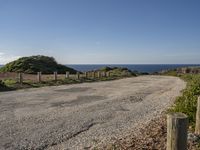 a view of a paved road in the middle of the day with the ocean in the background