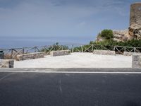 the bench is next to a concrete tower overlooking the water on a hill side,