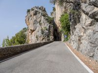 an empty road in front of a cliff face with an opening on the side of it