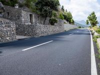 a long empty road between tall rocks and bushes by the ocean in greece on a sunny day
