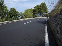a man riding his bike along the side of a road down to a river side