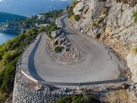 a curved mountain road on the edge of a cliff with the ocean in the background