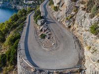 a curved mountain road on the edge of a cliff with the ocean in the background