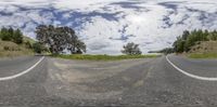 a view down the road and towards trees on either side of it with clouds in the sky