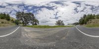 a view down the road and towards trees on either side of it with clouds in the sky