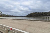 view of a paved road by water with white fenced in areas across from it