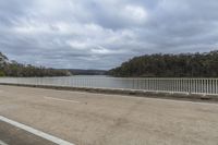 view of a paved road by water with white fenced in areas across from it