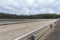 a freeway over the road with a wooden railing and railing around it to a forest