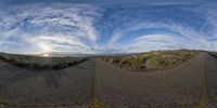 a double image of two roads running along side each other with some clouds and a blue sky in the background