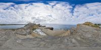 the view of the ocean through the spherical lens of a landscape and rock formation on an overcast day