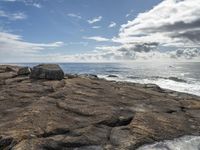 a photo taken by someone looking out over the ocean on rocks in the foreground is water and some sky