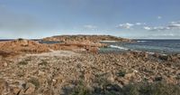 view of rocky shores, near beach of shoreline with clear blue water and sky in background