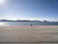 a person sitting on the beach in front of the ocean, looking at the water