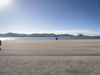 a person sitting on the beach in front of the ocean, looking at the water