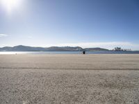 a person sitting on the beach in front of the ocean, looking at the water