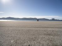 a person sitting on the beach in front of the ocean, looking at the water