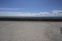 a beach area with concrete wall and ocean in background and sign that says keep off