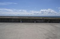 a beach area with concrete wall and ocean in background and sign that says keep off