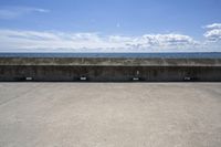 a beach area with concrete wall and ocean in background and sign that says keep off