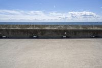 a beach area with concrete wall and ocean in background and sign that says keep off