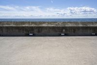 a beach area with concrete wall and ocean in background and sign that says keep off