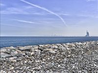 rocks and stones are strewn on the beach by the ocean with the city skyline in the background