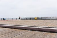 the wooden floor of a pier with a yellow surf board in the water behind it