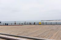 the wooden floor of a pier with a yellow surf board in the water behind it