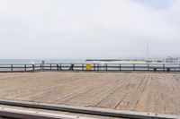 the wooden floor of a pier with a yellow surf board in the water behind it