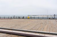 the wooden floor of a pier with a yellow surf board in the water behind it