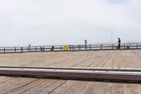 the wooden floor of a pier with a yellow surf board in the water behind it