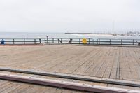 the wooden floor of a pier with a yellow surf board in the water behind it