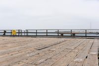 the wooden floor of a pier with a yellow surf board in the water behind it