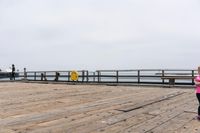 the wooden floor of a pier with a yellow surf board in the water behind it