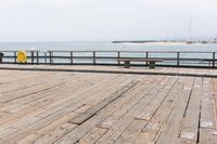 the wooden floor of a pier with a yellow surf board in the water behind it