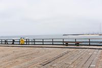 the wooden floor of a pier with a yellow surf board in the water behind it