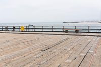 the wooden floor of a pier with a yellow surf board in the water behind it