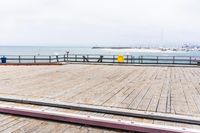 the wooden floor of a pier with a yellow surf board in the water behind it