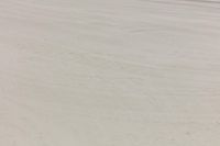 a man on skis riding down the street in the sand and water while another sits beside him