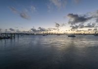 several boats are in the water at dusk near the city skylines with a cloud formation