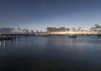 several boats are in the water at dusk near the city skylines with a cloud formation