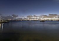 several boats are in the water at dusk near the city skylines with a cloud formation