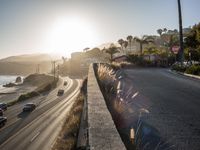 a beach side road with cars driving on it with a bright sun in the background