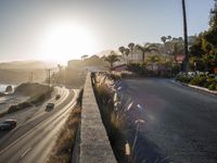 a beach side road with cars driving on it with a bright sun in the background